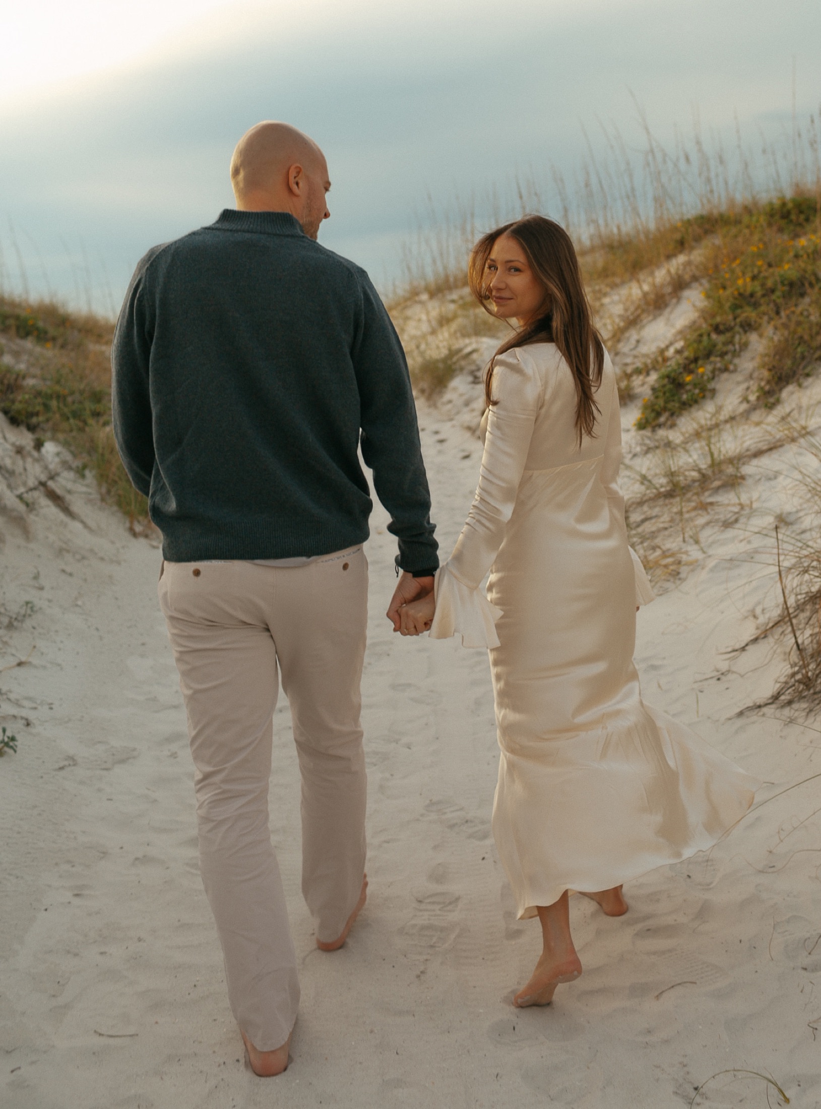 Couple walking along beach dunes