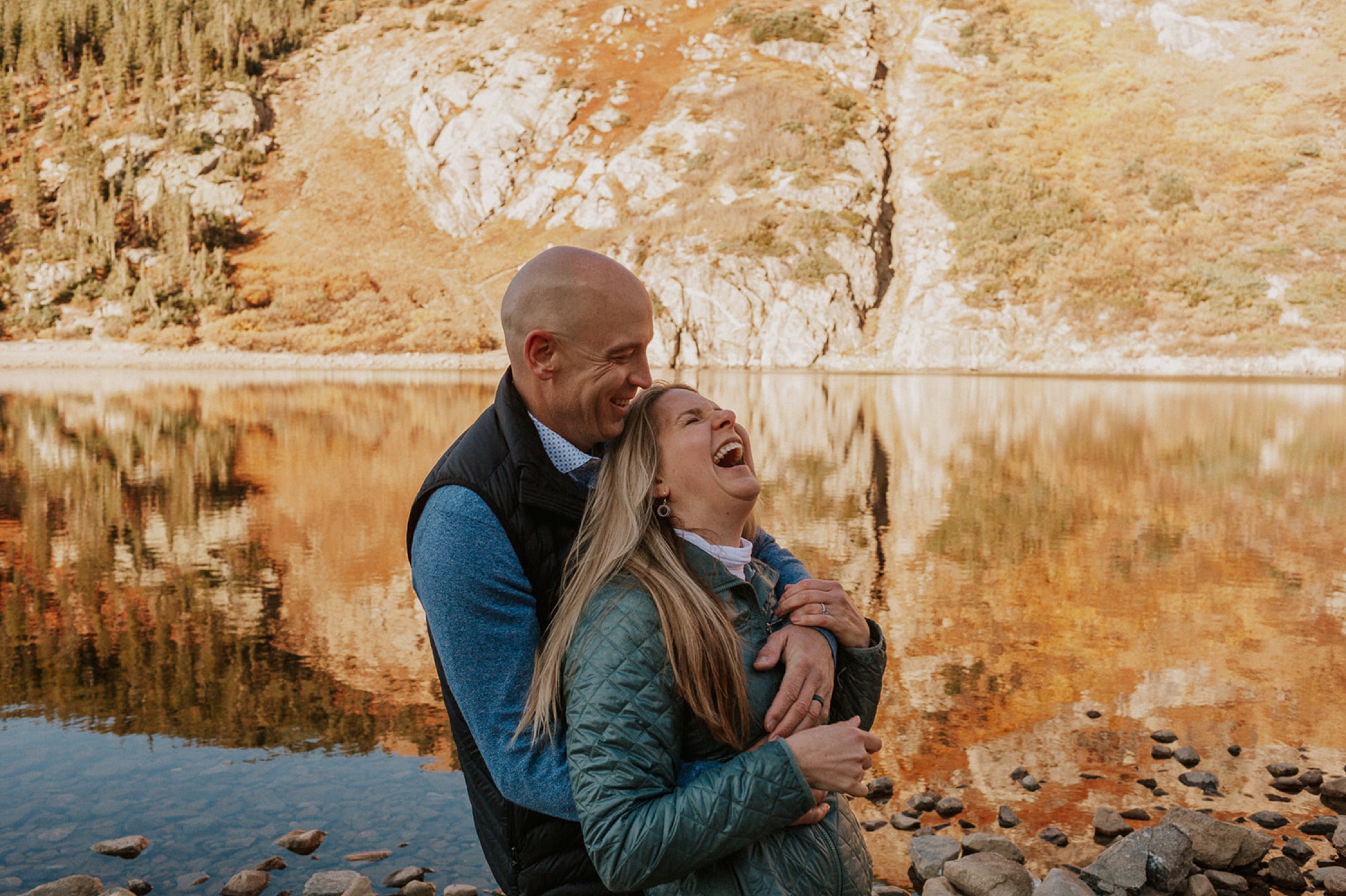 Couple laughing beside a mountain lake